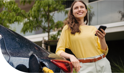 Femme souriante avec accoudée sur une voiture avec un téléphone en main