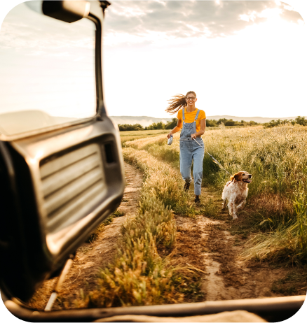 Femme avec un chien en laisse qui court vers une voiture